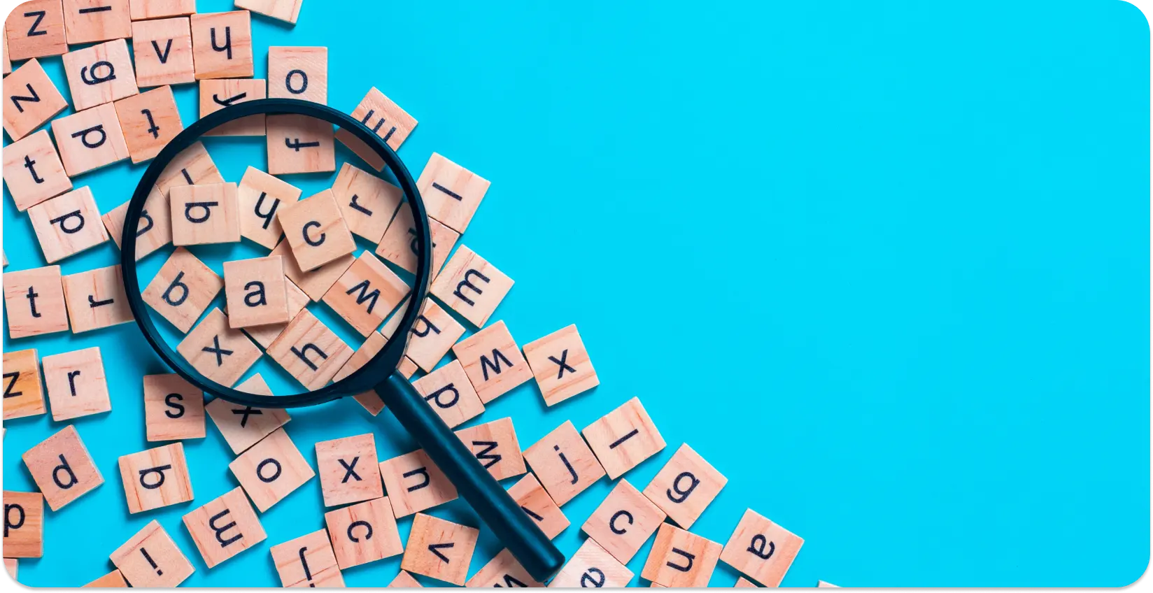 Magnifying glass focusing on scattered alphabet tiles representing language study.