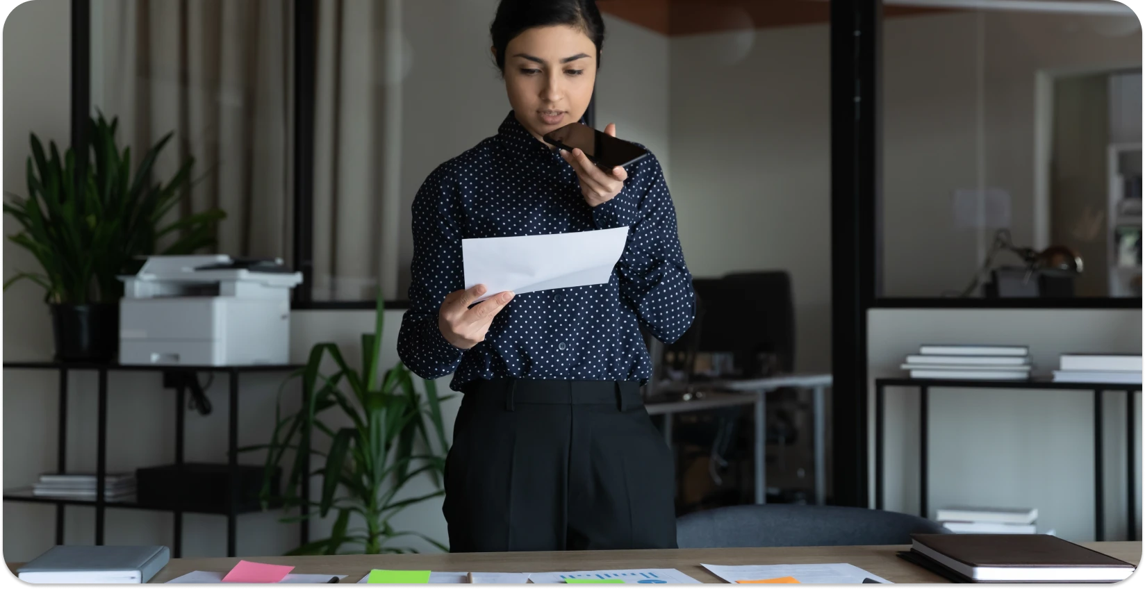Woman reviews documents while recording a voice memo for transcription.